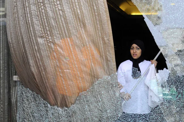 A hotel employee cleans smashed glass of the facade of a hotel that was attacked by gunmen, near the pyramids of Giza, Egypt, 07 January 2016. According to reports, a group of men fired fireworks and birdshots towards a hotel near the famous pyramids of Giza, southwest of Cairo, causing damage to the windows of a bus outside the building and the facade of the hotel. No casualties were reported in the attack, while one man was arrested from the scene. (Photo by Nameer Galal/EPA)