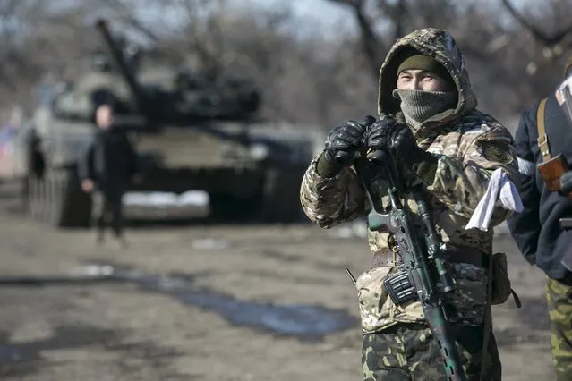 A fighter with the separatist self-proclaimed Donetsk People's Republic Army stands guard at a checkpoint along a road from the town of Vuhlehirsk to Debaltseve in Ukraine, in this picture taken February 18, 2015. (Photo by Baz Ratner/Reuters)