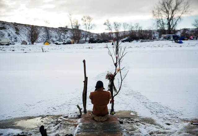 Army veteran Nick Biernacki, of Indiana, prays at Cannonball River at the Oceti Sakowin camp where people have gathered to protest the Dakota Access oil pipeline in Cannon Ball, N.D., December 4, 2016. Tribal elders have asked the military veterans joining the large Dakota Access pipeline protest encampment not to have confrontations with law enforcement officials, adding the group is there to help out those who've dug in against the four-state, $3.8 billion project. (Photo by David Goldman/AP Photo)