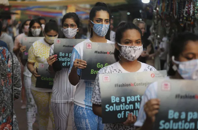 Indian fashion students, wearing anti-pollution masks, hold placards as they march through a market place for creating awareness on air pollution in New Delhi, India, Friday, November 2, 2018. With air quality reduced to “very severe” in the Indian capital region, authorities are bracing for a major Hindu festival featuring massive fireworks that threatens to cloak New Delhi with more toxic smog and dust. (Photo by Altaf Qadri/AP Photo)