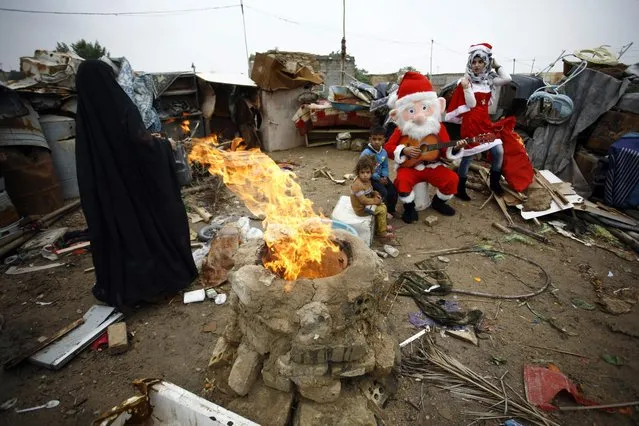 An Iraqi odontology student dressed in a Santa Claus outfit distribute gifts to impoverished children outside their shanty home in the Iraqi holy Shiite city of Najaf on December 25, 2016. (Photo by Haidar Hamdani/AFP Photo)