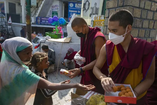 Exile Tibetan Buddhist monks distribute sweets and packets of juice to the public to celebrate the 86th birthday of their spiritual leader the Dalai Lama, outside the gate of their monastery in Dharmsala, India, Tuesday, July 6, 2021. (Photo by Ashwini Bhatia/AP Photo)