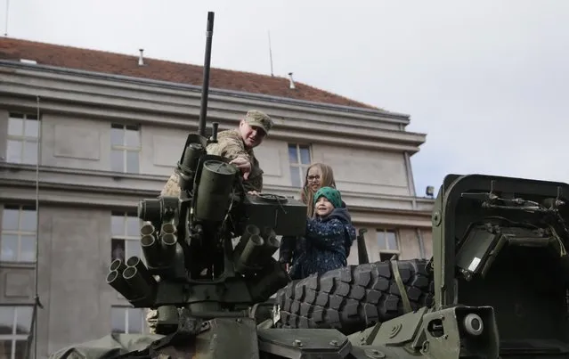 A US army soldier shows a gun mounted on top of a stryker armored vehicle to children during a stop of his convoy in Prague, Czech Republic, Tuesday, March 31, 2015. (Photo by Petr David Josek/AP Photo)
