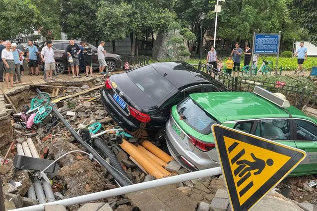 Damaged cars rest on debris after heavy rains hit the city of Zhengzhou causing floods in China's central Henan province on July 21, 2021. (Photo by AFP Photo/China Stringer Network)