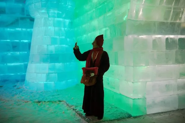 A Tibetan Buddhist monk takes a photo with his smartphone as he visits ice sculptures illuminated by coloured lights at the Harbin Ice and Snow Festival to celebrate the new year in Harbin on January 5, 2017. (Photo by Nicolas Asfouri/AFP Photo)