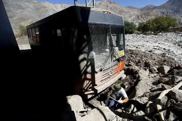 A man digs up his bus at an area which was hit by the floods at Los Loros town, April 7, 2015. (Photo by Ivan Alvarado/Reuters)
