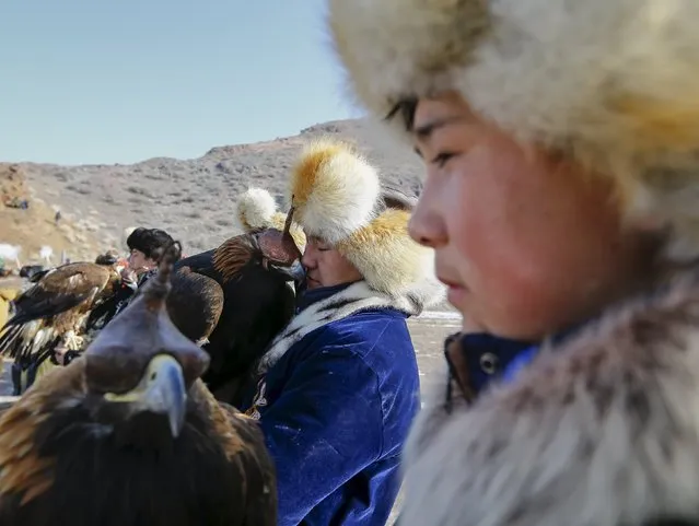 Hunters hold their tamed golden eagles at a parade during the traditional hunting contest outside the village of Nura, east from Almaty, Kazakhstan, February 13, 2016. (Photo by Shamil Zhumatov/Reuters)