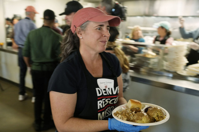 Volunteer Dana Cohen carries plates of food to guests at the annual Thanksgiving banquet at the Denver Rescue Mission on Wednesday, November 22, 2023, in Denver. Cohen and 40 other volunteers served the more than 500 guests at the meal, which closes out the organization's holiday week events. (Photo by David Zalubowski/AP Photo)