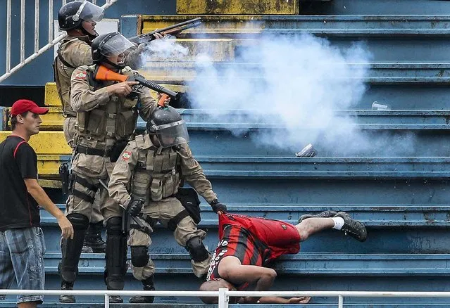 Police fire rubber bullets as they help an Atletico Paranaense fan during clashes between Vasco da Gama soccer fans and Atletico Paranaense fans at their Brazilian championship match in Joinville in Santa Catarina, on December 8, 2013. Dozens of fans fought a savage battle on the terraces at the match on Sunday, interrupting play for more than one hour and leaving at least three people reportedly in serious condition. (Photo by Carlos Moraes/Agencia O Dia)