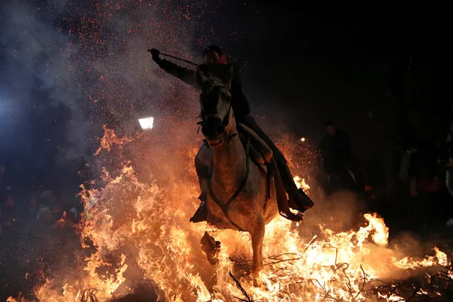 A woman rides a horse through flames during the annual “Luminarias” celebration on the eve of Saint Anthony's day, Spain's patron saint of animals, in the village of San Bartolome de Pinares, northwest of Madrid, Spain, January 16, 2019. (Photo by Susana Vera/Reuters)