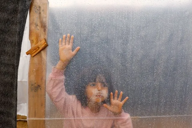 A displaced Palestinian girl looks through a plastic sheet covering a shelter at a tent camp, following a rainfall, as the conflict between Israel and Palestinian Islamist group Hamas continues, in Khan Younis in the southern Gaza Strip on November 15, 2023. (Photo by Ibraheem Abu Mustafa/Reuters)