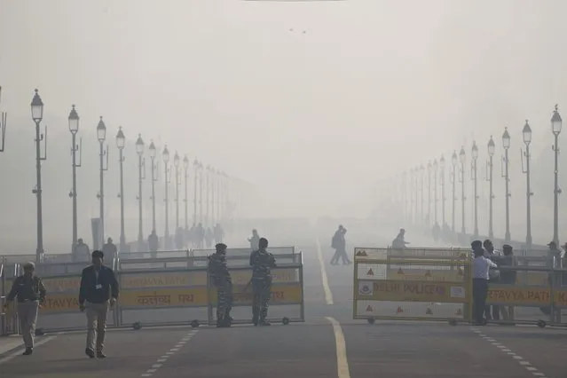 Security officers stand guard enveloped by smog early morning in New Delhi, India, Wednesday, December 13, 2023. The city is witnessing an increase in the pollution level, which continued to stay within the very poor category. (Photo by Manish Swarup/AP Photo)