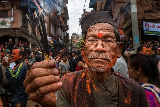 A devotee holds incense sticks while celebrating the Sindoor Jatra Festival on April 15, 2015 in Thimi, Nepal. Sindoor Jatra Festival is celebrated each year in Thimi, on the outskirts of Kathmandu, to welcome the Nepali New Year and celebrate the coming of spring. During the Festival, devotees are smeared with vermillion powder and 30 chariots containing the images of several gods and goddesses are carrying by the devotees around the town, while others sing, dance and play musical instruments. (Photo by Omar Havana/Getty Images)