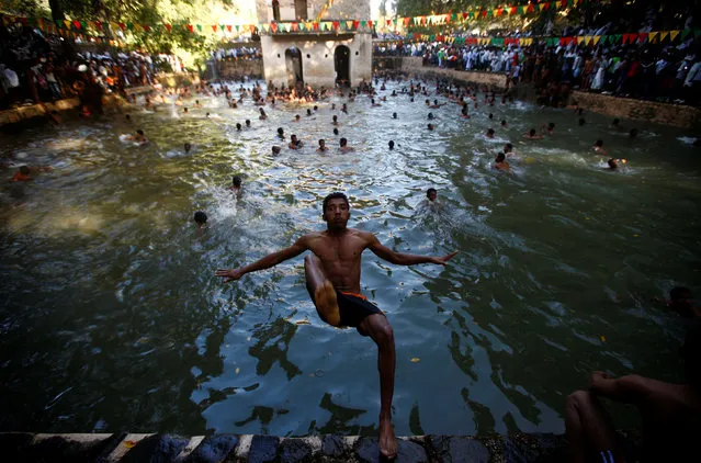 A faithful jumps into the waters of the Fasilides Bath as part of a ceremony in which the waters are blessed by the priest of the Ethiopian Orthodox Tewahedo Church during the second day of Timket in Gondar, Ethiopia, January 19, 2017. “Timket”, the greatest Ethiopian festival of the year, is to commemorate Jesus Christ's baptism in the Jordan River by John the Baptist. (Photo by Tiksa Negeri/Reuters)