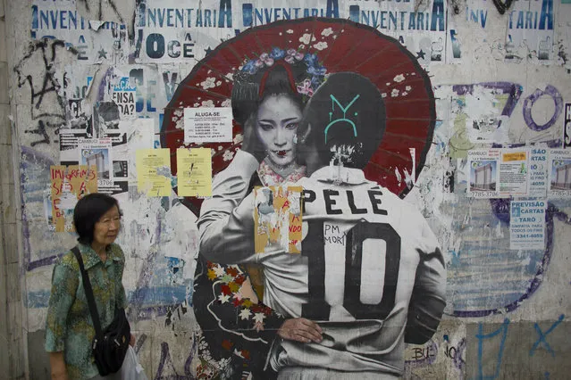 In this December 27, 2018 photo, a woman walks by a mural of Brazilian soccer legend Pele hugging a Geisha in Sao Paulo, Brazil's Asian neighborhood of Liberdade, the area where an influential Japanese-language newspaper ran its last print edition on Jan. 1, 2019. The arrival of the first Japanese immigrants to Brazil was the result of negotiations between Japan and Sao Paulo state, where most Japanese-Brazilians still live. (Photo by Victor R. Caivano/AP Photo)