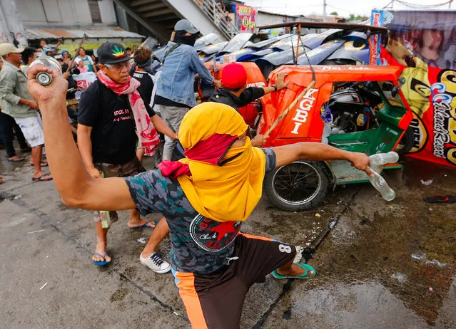 An informal settler throws a bottle at riot police during a demolition in Quezon City, northeast of Manila, Philippines, 09 March 2016. According to Sheriff Bienvenido Reyes Jr. of the Quezon City Regional Trial Court Branch 98, a court ordered the demolition of some 80 homes in a 2,000-square meter private property. Informal settlers called for the suspension of the demolition job until they are provided with a decent relocation site. (Photo by Mark R. Cristino/EPA)