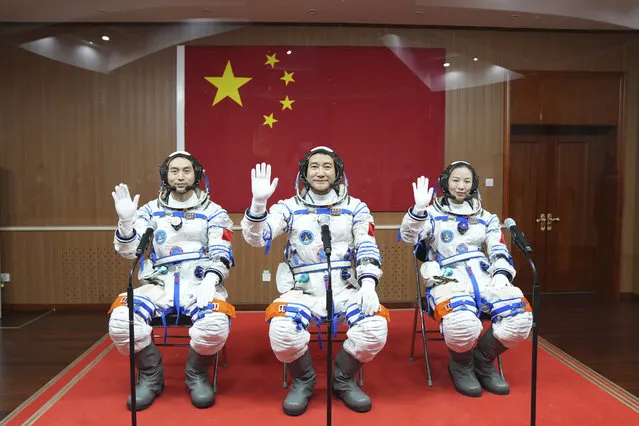 In this photo released by Xinhua News Agency, Chinese astronauts from left, Ye Guangfu, Zhai Zhigang and Wang Yaping wave from behind glass panel before departing for their Shenzhou-13 crewed space mission at the Jiuquan Satellite Launch Center in northwest China, October 15, 2021. Shortly ahead of sending a new three-person crew to its space station, China on Friday renewed its commitment to international cooperation in the peaceful use of space. (Photo by Li Gang/Xinhua via AP Photo)