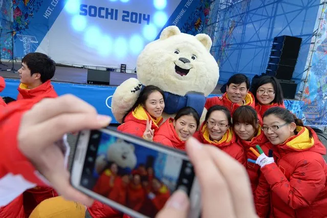 China's Olympic delegation members pose flanked by Sochi Olympics Polar Bear mascot at the Olympic Park's Medal Plaza two days prior to the start of the 2014 Sochi Winter Olympics, on February 5, 2014 in Sochi. (Photo by Andrej Isakovic/AFP Photo)