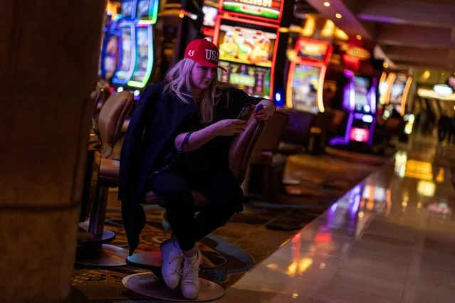 A supporter of Republican presidential candidate and former U.S. President Donald Trump looks at her phone by slot machines at Treasure Island Resort & Casino after attending a Nevada caucus night party in Las Vegas, Nevada on February 9, 2024. (Photo by Carlos Barria/Reuters)