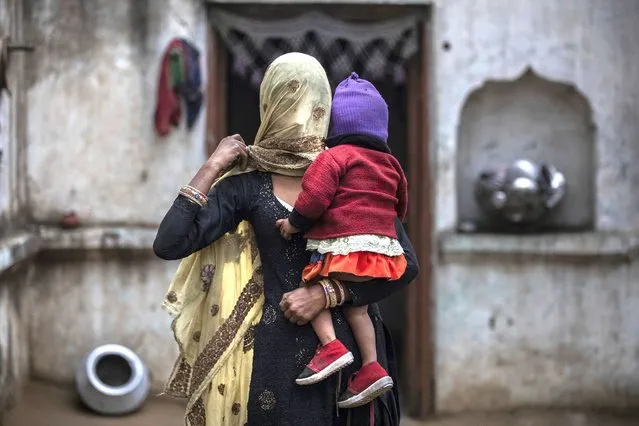 In this Tuesday, January 22, 2019 photo, the wife of Saghir Khan,Anisa Khan, holds their daughter, Alfisa, at the family's house in Mirzapur. Saghir was beaten by a group of Hindus after being spotted transporting cows. (Photo by Bernat Armangue/AP Photo)