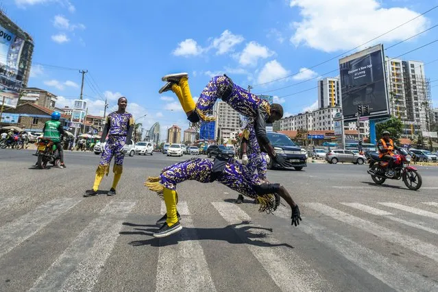 People in colorful costumes perform acrobatics for drivers waiting at red lights in Nairobi, Kenya on February 20, 2024. (Photo by Gerald Anderson/Anadolu via Getty Images)