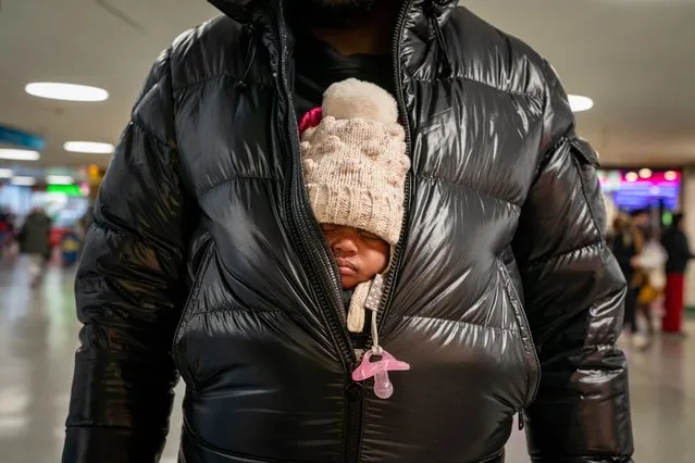 A person holds a small child under their coat at Penn Station on November 24, 2021 in New York City. AAA Travel predicts 53.4 million people will travel for the Thanksgiving holiday, an increase of 13% from 2020. (Photo by David Dee Delgado/Getty Images)