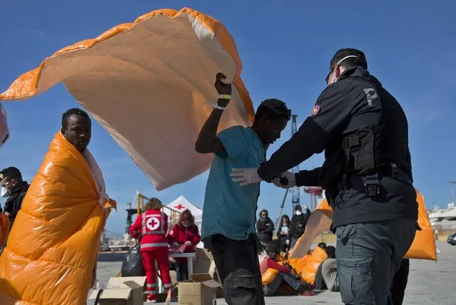 A migrant is inspected by policemen after disembarking from the Norwegian vessel Siem Pilot at Pozzallo's harbour, Italy, March 29, 2016. (Photo by Antonio Parrinello/Reuters)