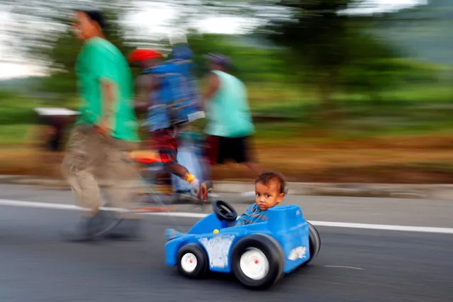 Esnayder, 2, a migrant boy from Honduras is pulled in a toy car by his father Hever Calero, as they take part in a caravan to the U.S. border, near Villa Mapastepec, Mexico on November 22, 2021. (Photo by Jose Luis Gonzalez/Reuters)