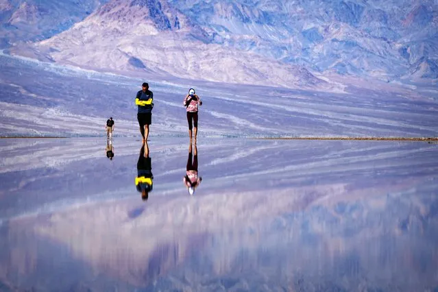 Vinaya Vijay, right, and Vijay Parthasarathy wade through water at Badwater Basin, Thursday, February 22, 2024, in Death Valley National Park, Calif. The basin, normally a salt flat, has filled from rain over the past few months. (Photo by John Locher/AP Photo)