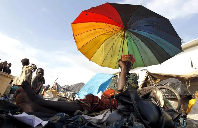 A Burundian refugee holds an umbrella as they gather on the shores of Lake Tanganyika in Kagunga village in Kigoma region in western Tanzania, to wait for MV Liemba to transport them to Kigoma township, May 17, 2015. (Photo by Thomas Mukoya/Reuters)