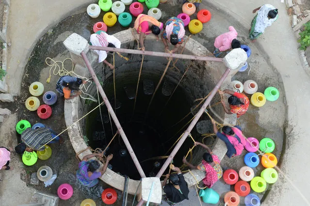 Indian residents fetch drinking water from a well in the outskirts of Chennai on May 29, 2019. Water levels in the four main reservoirs in Chennai have fallen to one of its lowest levels in 70 years, according to Indian media reports. (Photo by Arun Sankar/AFP Photo)