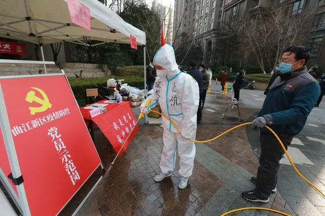 Government workers disinfect a work post with the sign “Model Community Party Post” outside a residential block in Xi'an city in northwest China's Shaanxi province Monday, January 3, 2022. (Photo by Chinatopix via AP Photo)