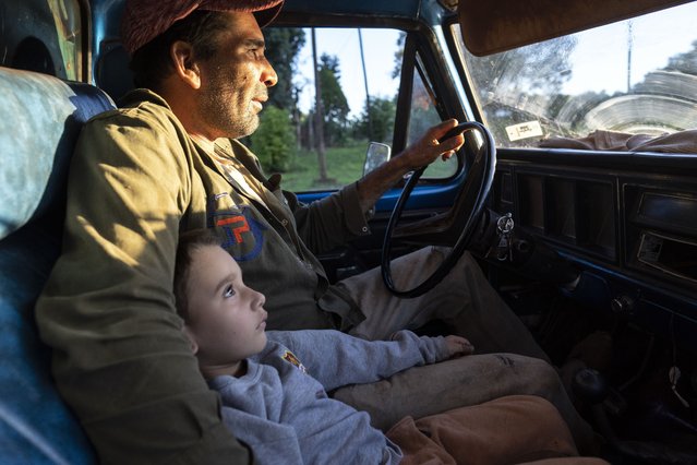 Yerba mate foreman Antonio Francisco Pereyra drives with his four-year-old son Facundo under his arm, to deliver weekly payments to his crew in Andresito, in Argentina's Misiones province, April 19, 2024. (Photo by Rodrigo Abd/AP Photo)