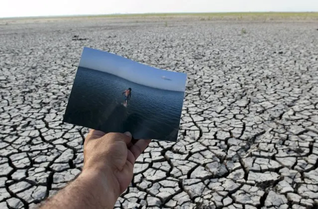 Photographer holds a photograph took in 2008, as he is on the dried ground at the Tisma lagoon wetland park due to drought affecting Tisma town, Nicaragua April 20,2016. (Photo by Oswaldo Rivas/Reuters)