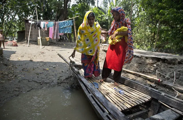 In this Friday, July 19, 2019 photo, a woman helps Imrana Khatoon, left, on to a boat to get to a hospital, while holding Khatoon's newborn baby outside her flood-affected home in Gagalmari, east of Gauhati, India. Khatoon, 20, delivered her first baby on a boat in floodwaters early Friday while on her way to a hospital, locals said. The woman and the newborn were brought back to their home without getting to hospital. They were however moved to a hospital on a boat to the nearby Jhargaon town because of unhygienic conditions due to floodwaters, Community health worker Parag Jyoti Das said. (Photo by Anupam Nath/AP Photo)