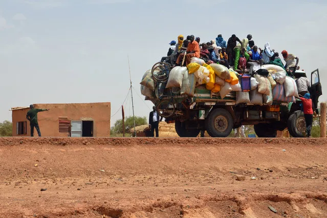 People ride in a loaded truck on June 19, 2019, by the police checkpoint where two policemen were killed and four injured by armed men during an overnight attack on June 18 at the police station at the northern entrance to Niamey, the first to happen at the gates of the capital of Niger, a country beset by recurring jihadist raids. Niger, a large, impoverished state in the heart of the fragile Sahel region, is grappling with attacks by jihadist groups in the west of the country, and raids by Boko Haram Islamists in the south, near the border with Nigeria. (Photo by Boureima Hama/AFP Photo)