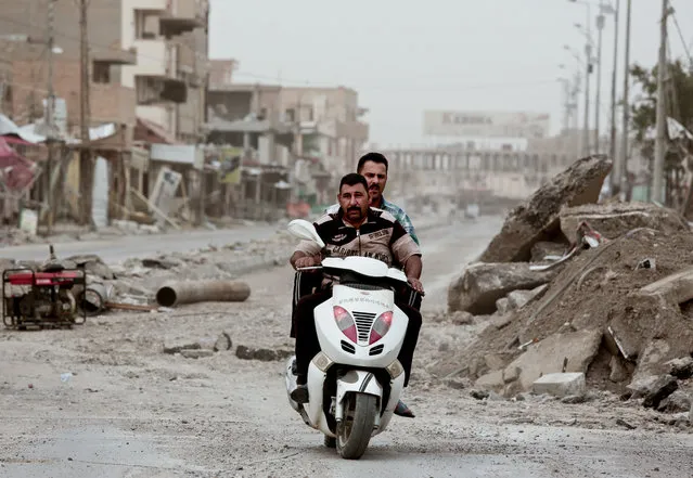 Policemen ride a motorbike near Haji Ziad Square in the city of Ramadi, Iraq, on March 20, 2016, passing rubble that remains weeks after government forces retook the city from Islamic State group militants. Entire city blocks were leveled by fighting, airstrikes and the scorched earth campaign waged by militants as they fled. “All they leave is rubble”, one counterterrorism officer said. (Photo by Maya Alleruzzo/AP Photo)