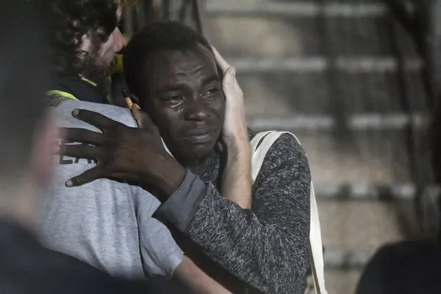 In this photo taken on Tuesday, August 20, 2019 a man cries as he hugs a crew member after disembarking from the Open Arms rescue ship on the Sicilian island of Lampedusa, southern Italy. An Italian prosecutor ordered the seizure of a rescue ship and the immediate evacuation of more than 80 migrants still aboard, capping a drama Tuesday that saw 15 people jump overboard in a desperate bid to escape deteriorating conditions on the vessel and Spain dispatch a naval ship to try to resolve the crisis. (Photo by Salvatore Cavalli/AP Photo)