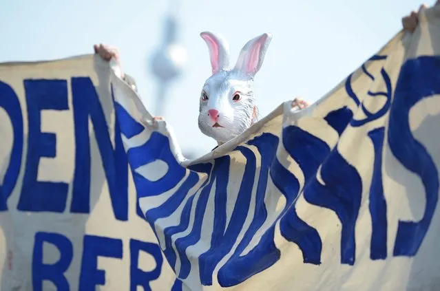 A woman wearing an Easter bunny mask helps to hold a banner during the traditional Easter March of the German peace movement, in Berlin, Germany, 19 April 2014. Several hundred people demonstrated for peace under the motto “War is made! We stand against that” at this year's Easter March in Berlin. (Photo by Rainer Jensen/EPA)