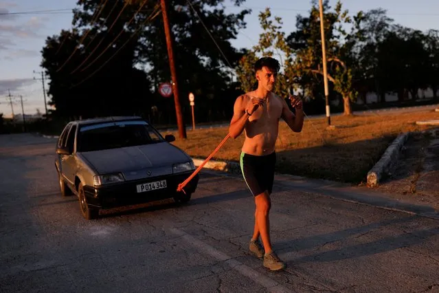 Christian Emanuel Castellanos Rangel, 22, pulls a car with a makeshift wood piece to tighten his scapulas during a training session in Sancti Spiritus, Cuba, January 30, 2022. (Photo by Amanda Perobelli/Reuters)