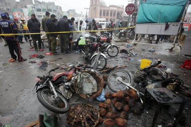 Members of crime scene unit and a bomb disposal team gather after a blast in a market, in Lahore, Pakistan on January 20, 2022. (Photo by Mohsin Raza/Reuters)