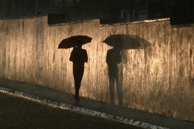 A pedestrian walks with an umbrella along a street during rainfall in Bengaluru on June 2, 2024. (Photo by Idrees Mohammed/AFP Photo)