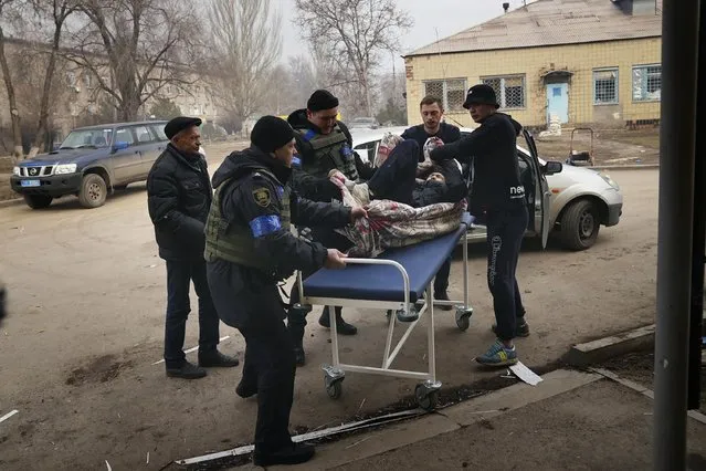 Ukrainian servicemen and volunteers carry a man injured during a shelling attack into hospital number 3 in Mariupol, Ukraine, Tuesday, March 15, 2022. (Photo by Evgeniy Maloletka/AP Photo)