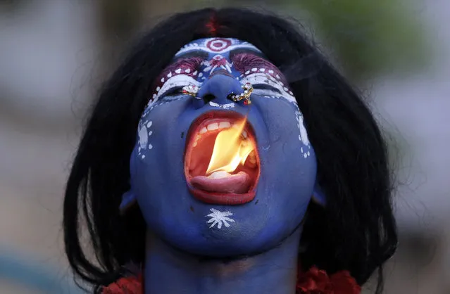 An Indian man dressed as Hindu Goddess Kali puts fire in his mouth during a procession to celebrate the Ram Navami festival in Allahabad, India, Friday, April 15, 2016. (Photo by Rajesh Kumar Singh/AP Photo)