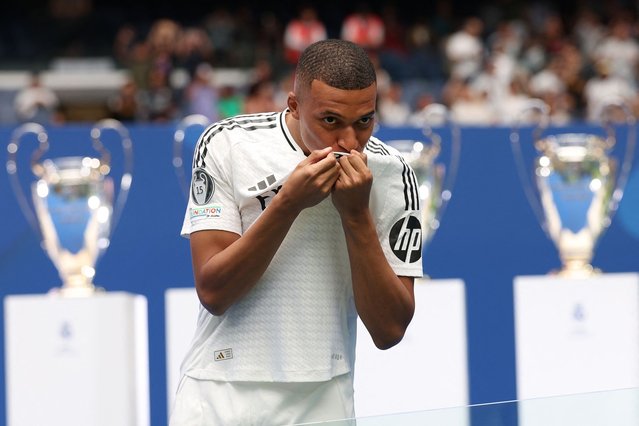 French forward Kylian Mbappe kisses his jersey during a first appearance as a Real Madrid player at the Santiago Bernabeu Stadium in Madrid on July 16, 2024, after signing his new five-season contract. Still celebrating Spain's Euro 2024 triumph, Real Madrid fans have even more to cheer this July 16, 2024, as French superstar Kylian Mbappe is officially presented to a packed-out Santiago Bernabeu stadium. (Photo by Pierre-Philippe Marcou/AFP Photo)