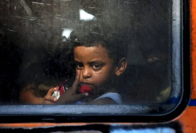 A migrant child of a family from Aleppo, Syria, looks out a window of a train at Gevgelija train station in Macedonia, near the border with Greece,  July 19, 2015. (Photo by Ognen Teofilovski/Reuters)