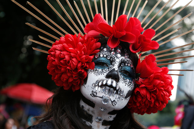 A woman dressed as Catrinas poses for a photo as she joins a parade on Mexico City's iconic Reforma avenue during celebrations for the Day of the Dead in Mexico, Saturday, October 26, 2019. (Photo by Ginnette Riquelme/AP Photo)