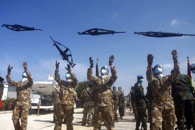 Indonesian U.N peacekeepers toss their rifles in the air during a ceremony to mark the transfer of authority between the outgoing and the newly appointed head of the mission at the UNIFIL headquarters in the southern Lebanese town of Naqoura, Lebanon, Monday, February 28, 2022. (Photo by Mohammed Zaatari/AP Photo)