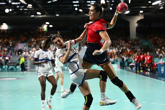 France's right wing #31 Lucie Granier (L) falls past Spain's left back #22 Lara Gonzalez during the Women's Preliminary Round Group B handball match between Spain and France of the Paris 2024 Olympic Games, at the Paris South Arena in Paris, on August 3, 2024. (Photo by Aris Messinis/AFP Photo)