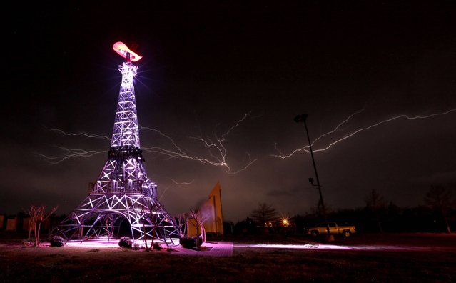 Lightning rips through the night sky Thursday, April 3, 2014, behind a replica Eiffel Tower in Paris, Texas, as a severe thunderstorm moved through the Southern part of Lamar County bringing high winds, rain and hail. (Photo by Sam Craft/AP Photo/The Paris News News)